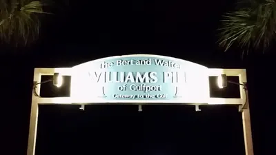 Lit Williams Pier entrance sign at night in Gulfport